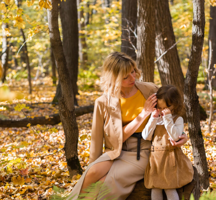 Caregiver and child sitting together outdoors, representing grief counseling and emotional support after loss