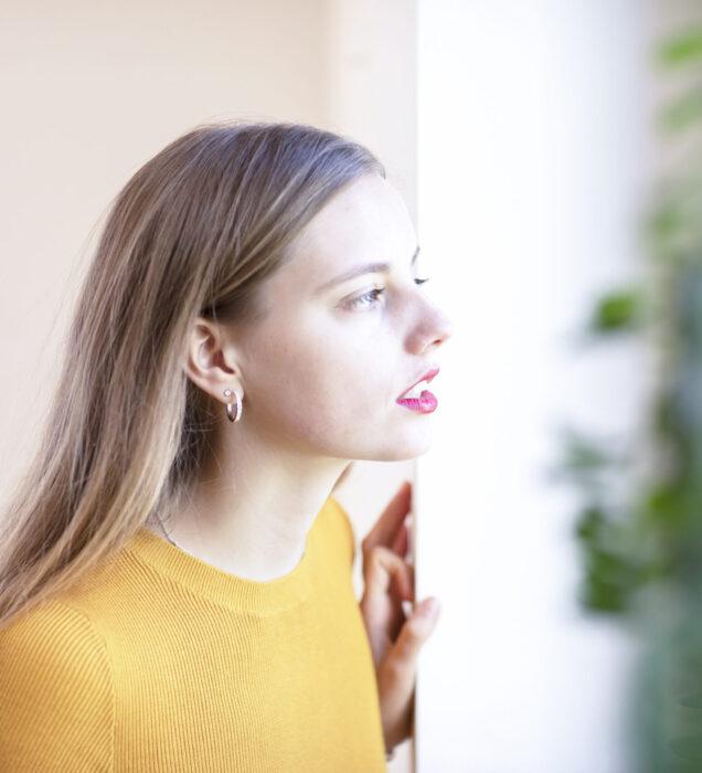 Young woman in Scottsdale, AZ looking out a window refecting on emotional healing through Dialectical Behavior Therapy (DBT)