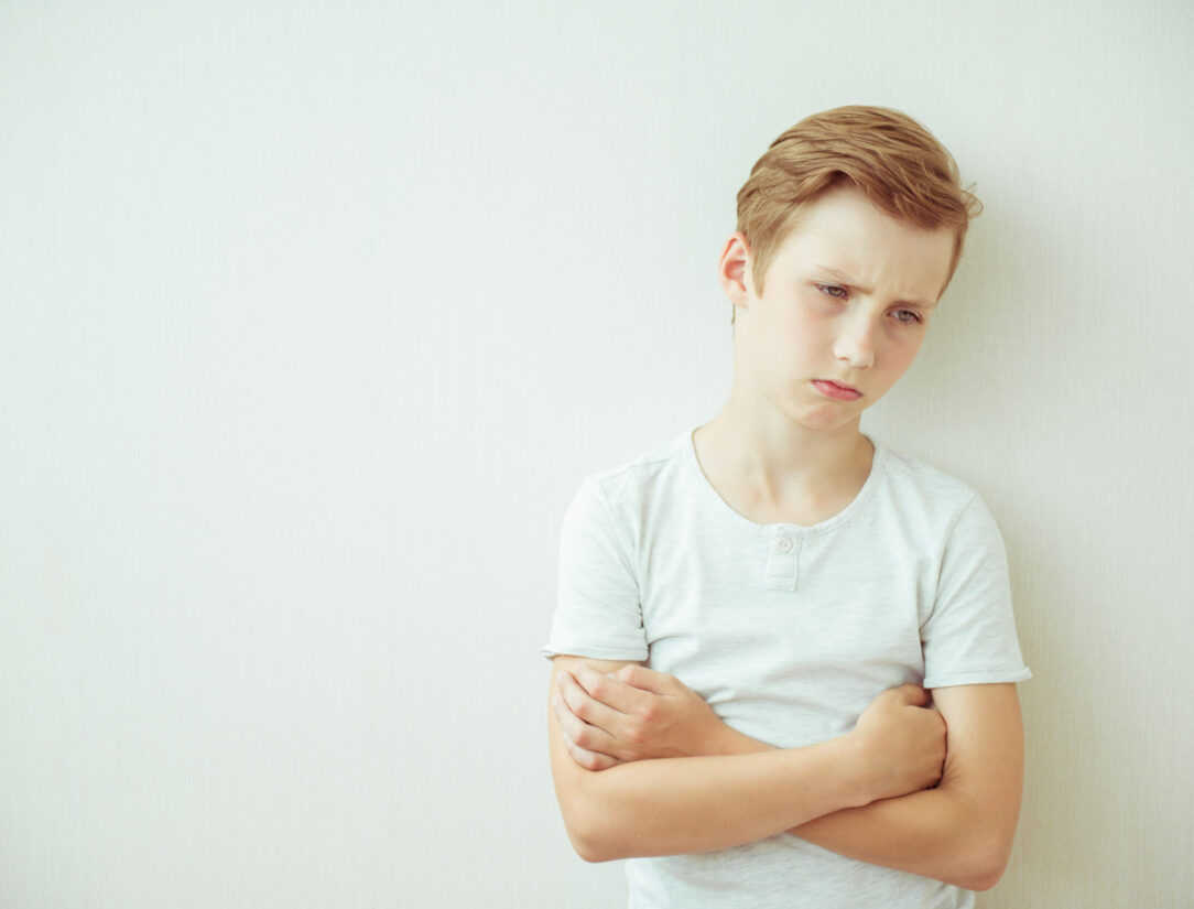 Frustrated teen boy stands with his arms crossed. Copy space Frustrated teen boy stands with his arms crossed. Copy space