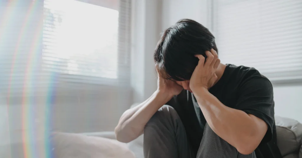 Person sitting alone with their head in their hands, representing anxiety, emotional distress, and feelings of overwhelm.
