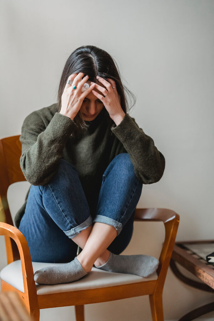 Anxiety - young woman holding her forehead as she deals with anxiety