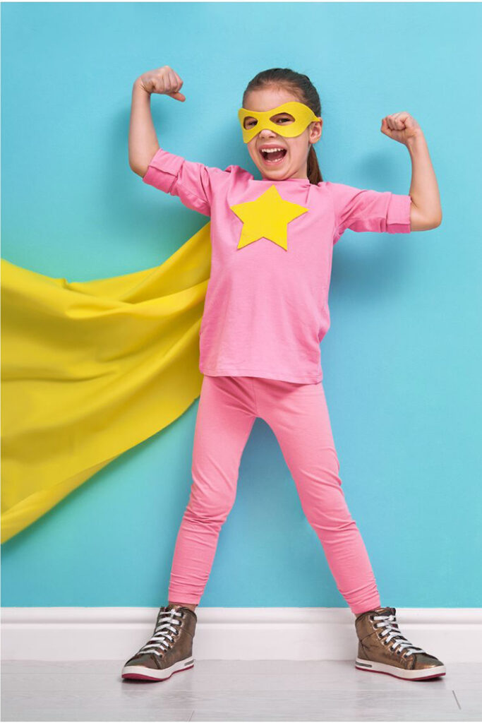 Child with ADHD - young girl with yellow mask, star on her chest and yellow cape wearing pink shirt and leggings